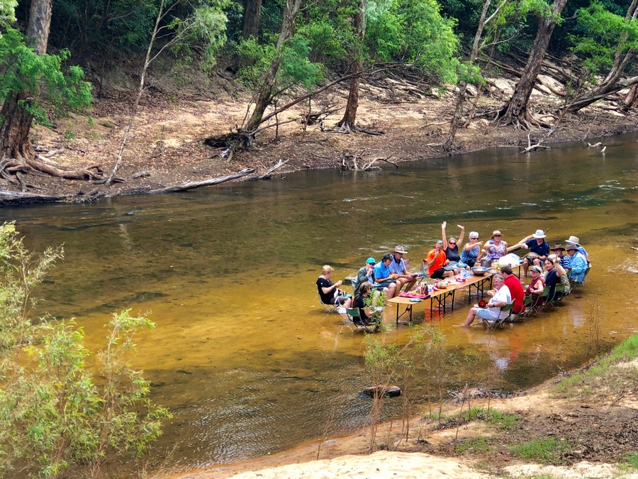 20 people having lunch in a river with tables and chairs