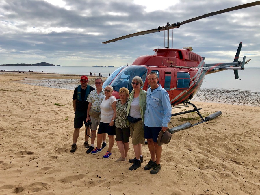group of people in front of helicopter on beach