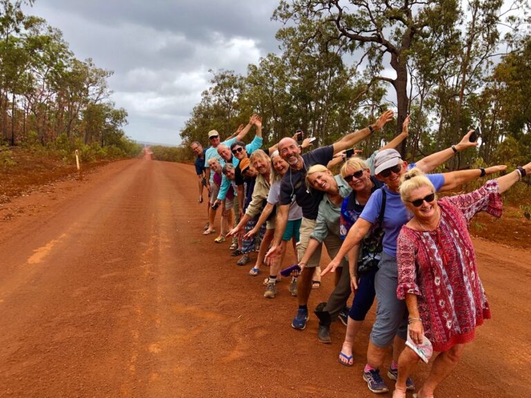group of people lined up on red dirt road