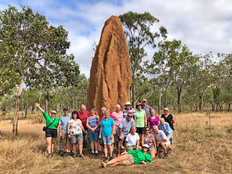 group of people in front of red, 5 metre tall termite mound