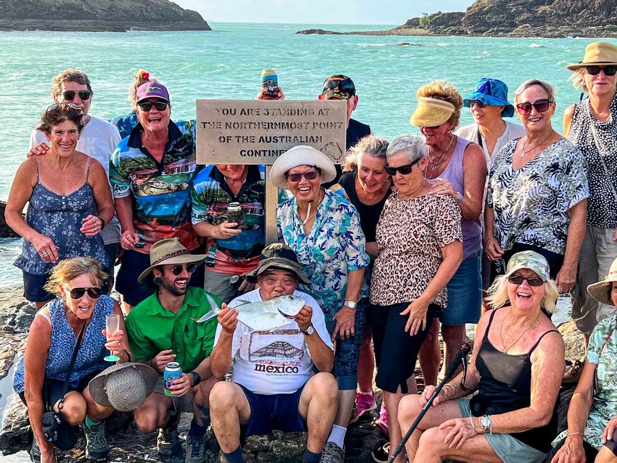 people at tip of cape york sign