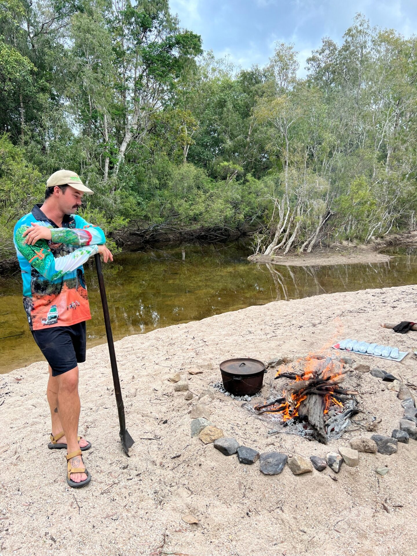 chef cooking on fire next to creek in cape york