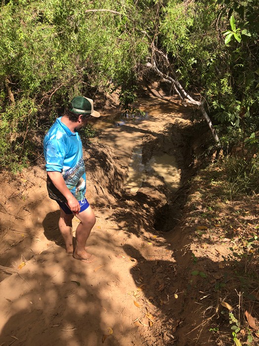man looking at steep 4wd track coming out of creek